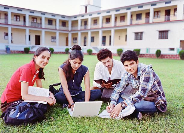 Group of Indian / Asian college students studying over the grass in the campus.
